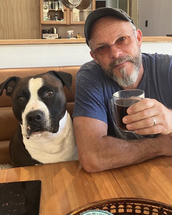 Ken King at the kitchen table with a coffee and his dog