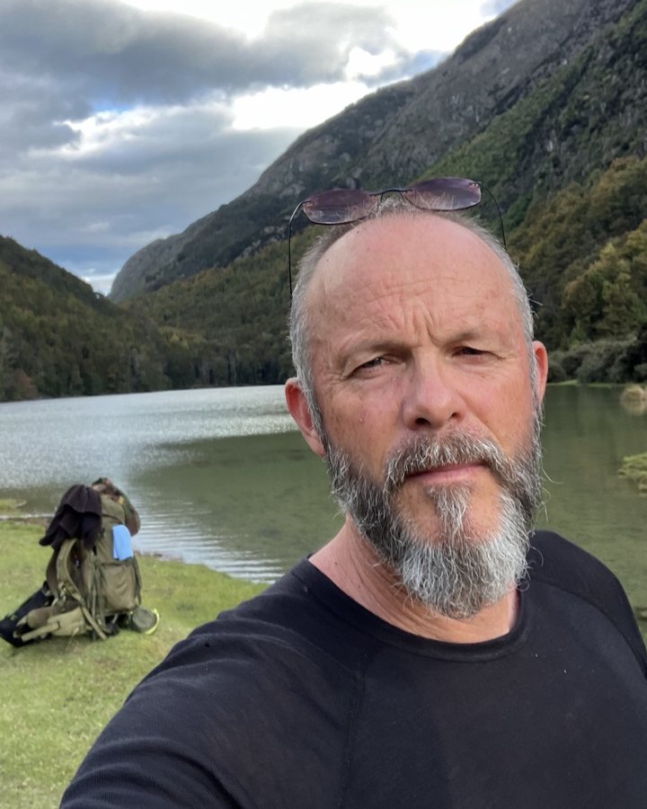 Ken King in the back country beside a mountain lake